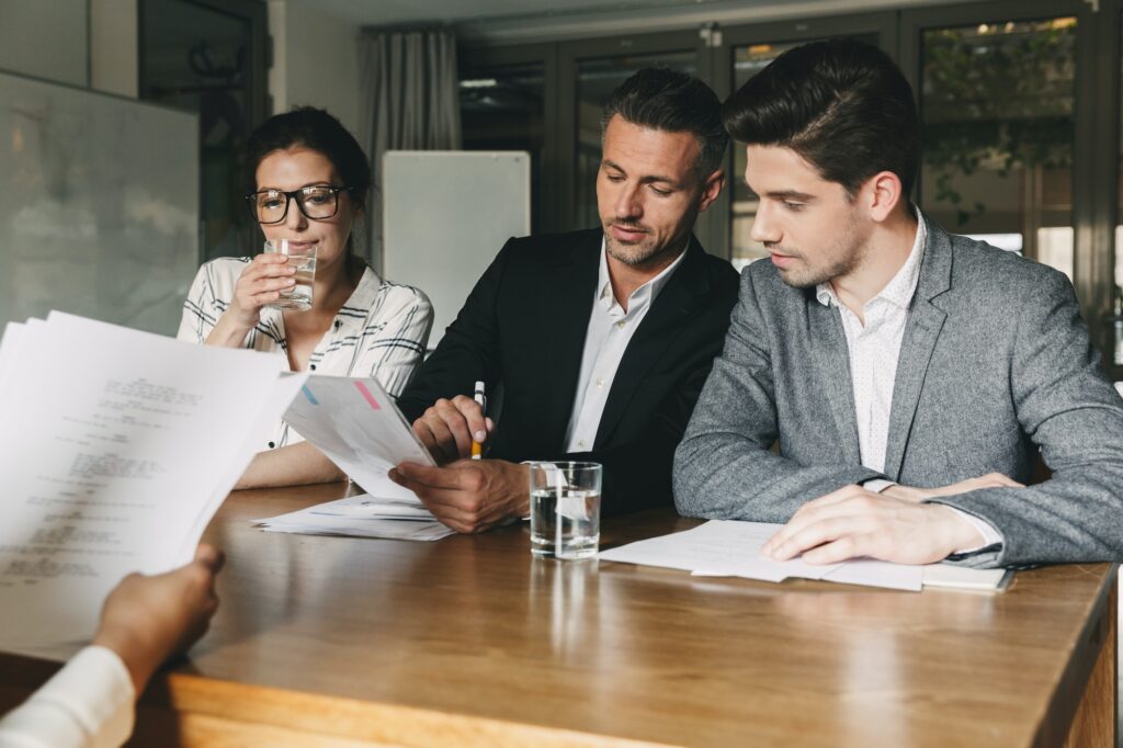 Group of caucasian employers in formal wear sitting at table in